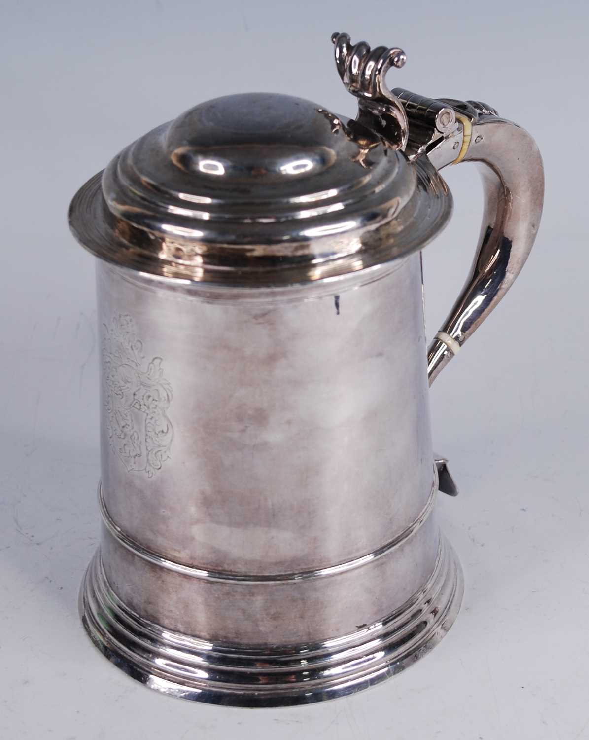 A George I silver lidded tankard, of flaring cylindrical form, the domed cover with scroll