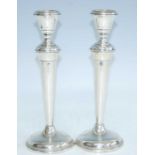 A pair of George V loaded silver table candlesticks, each column of knopped tapering form to a