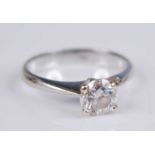 A white metal diamond solitaire ring, with a round brilliant cut diamond in a four-claw V shaped