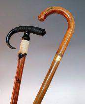 An early 20th century walking stick, having carved ebony and hoof handle leading to a malacca shaft,