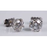 A pair of white metal diamond stud earrings, each comprising a round brilliant cut diamond in a