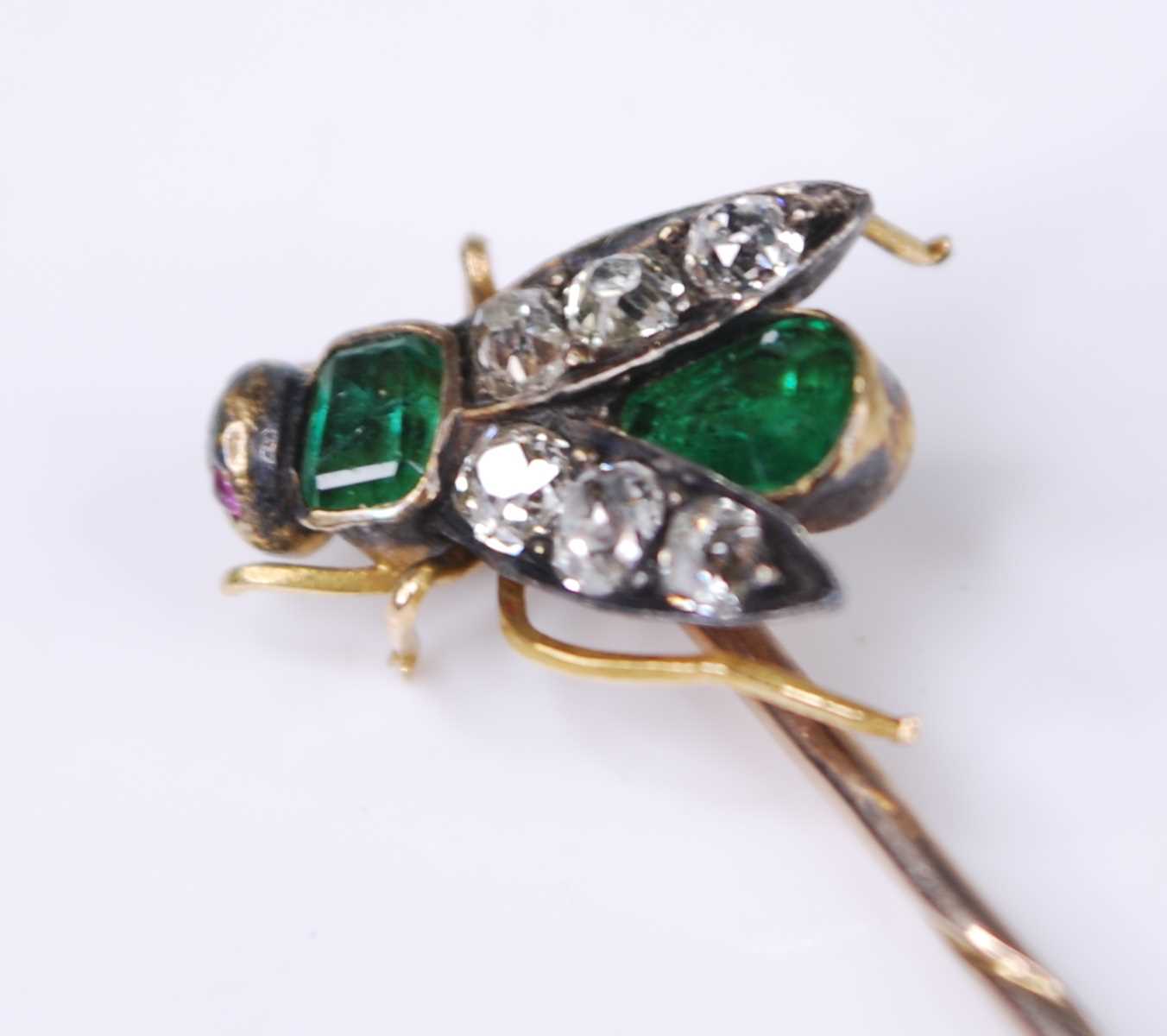 A yellow metal diamond, emerald and ruby stick pin in the form of a winged inset, set with a 3.9 x