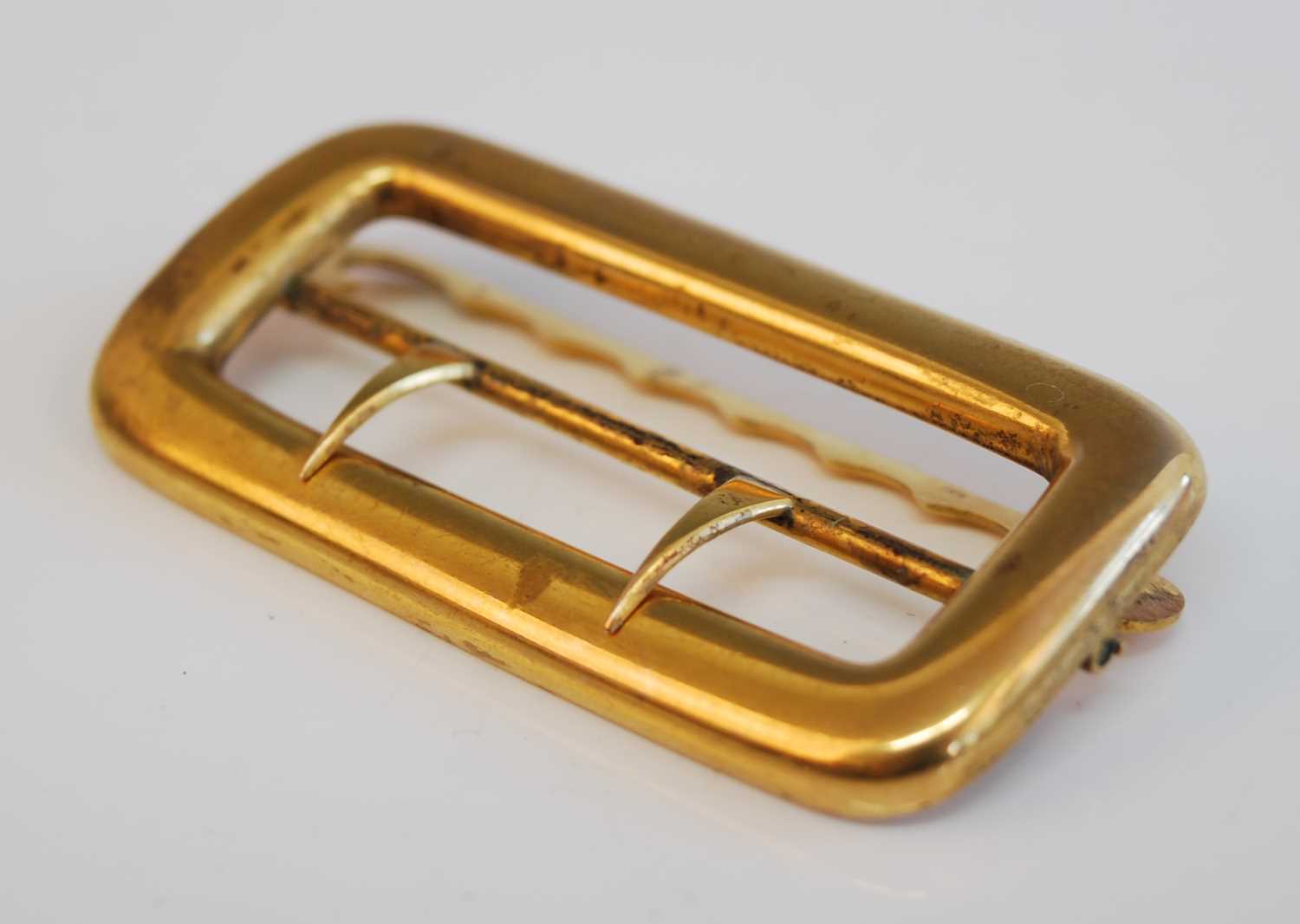 A 19th century yellow metal buckle, of shaped rectangular form with twin-pronged chape, the chape