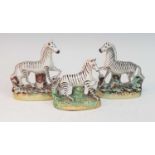 A collection of three circa 1860 Staffordshire models of zebras, each mounted upon a naturalistic