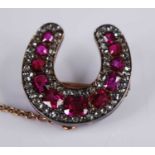 A late Victorian yellow metal, ruby and diamond horseshoe brooch, featuring eleven graduated oval