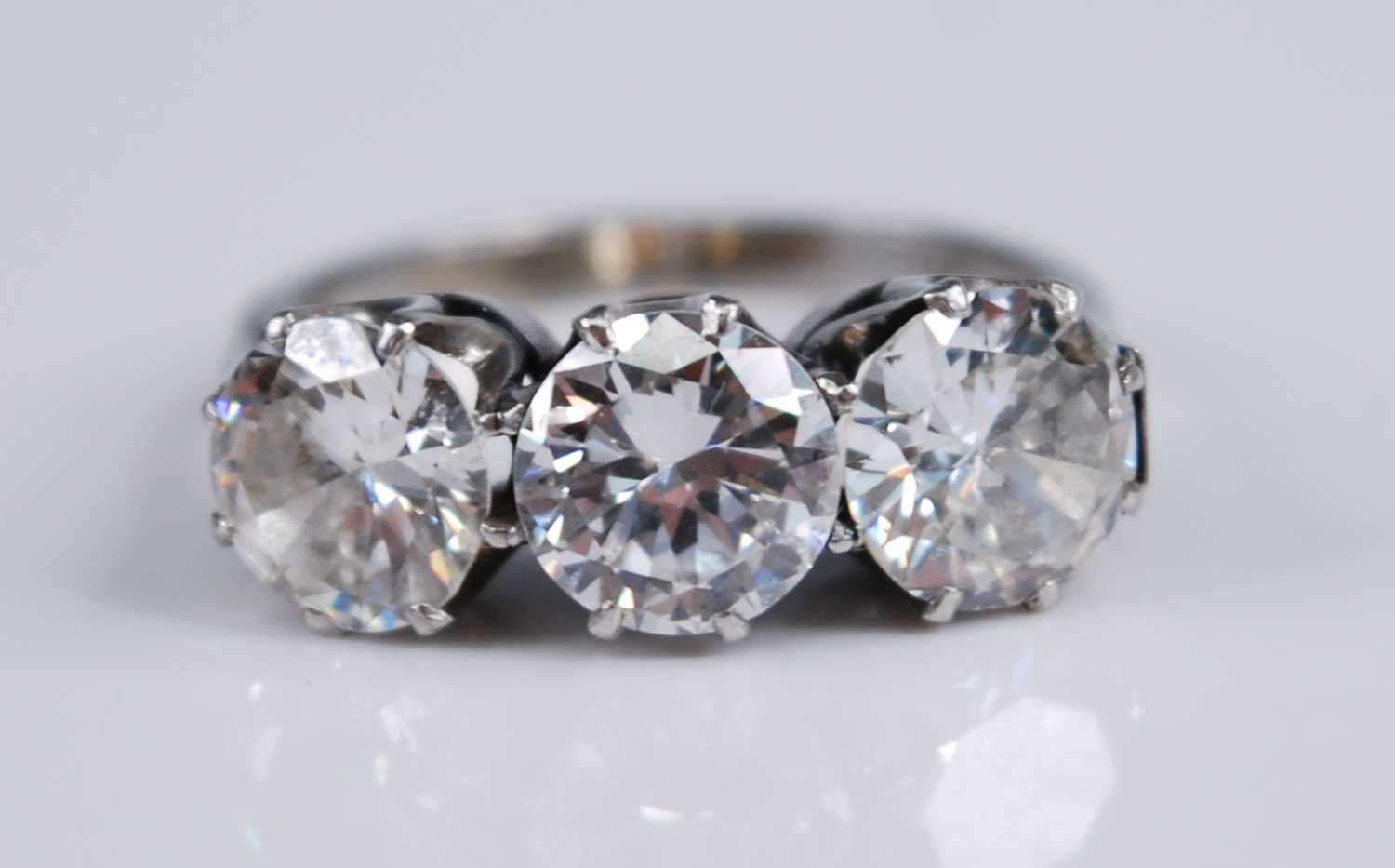 A white metal diamond three stone ring, comprising three round brilliant cut diamonds in claw - Image 2 of 7