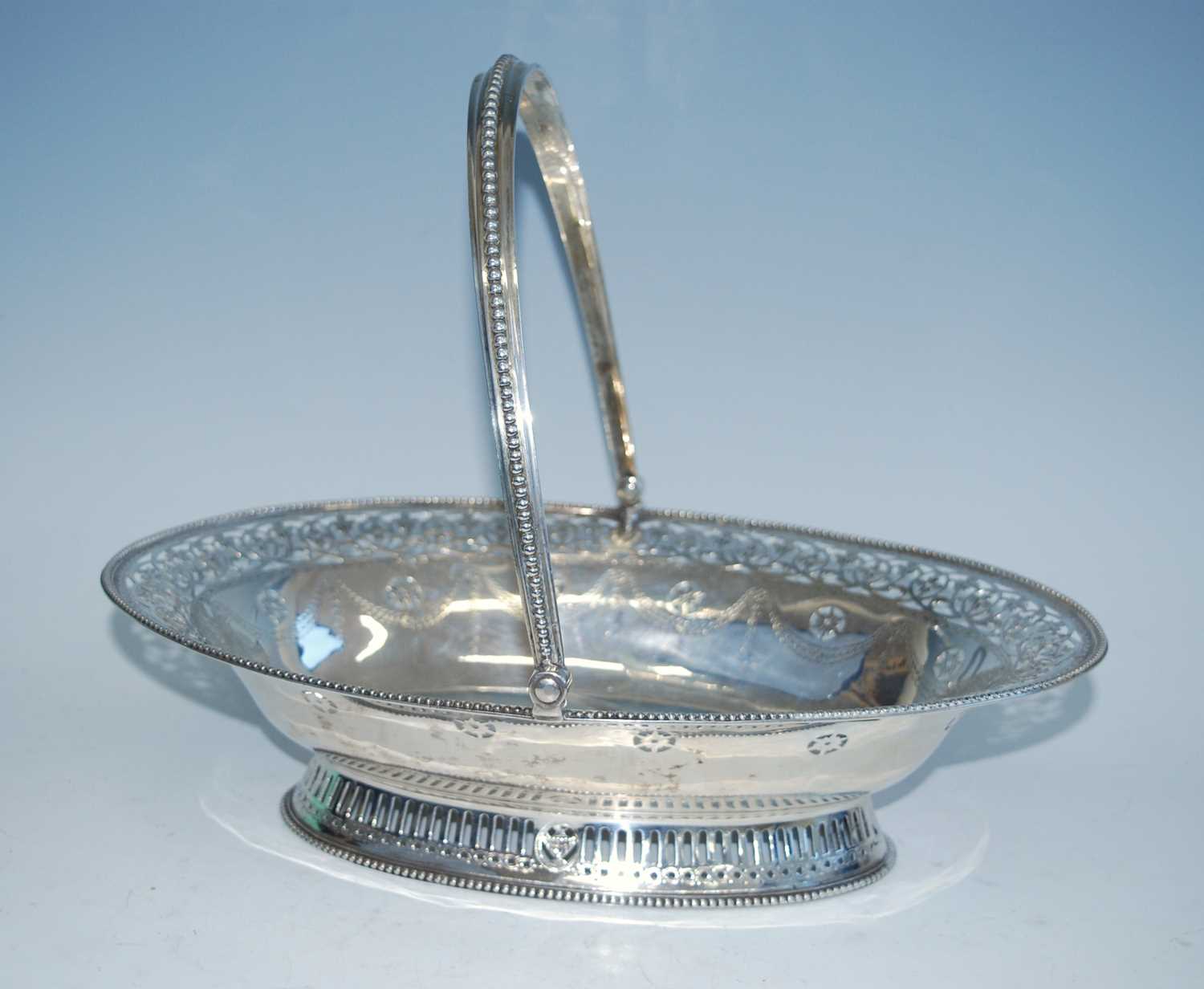 A George IV silver swing-handled cake basket, of oval form with beaded rims, pierced and engraved