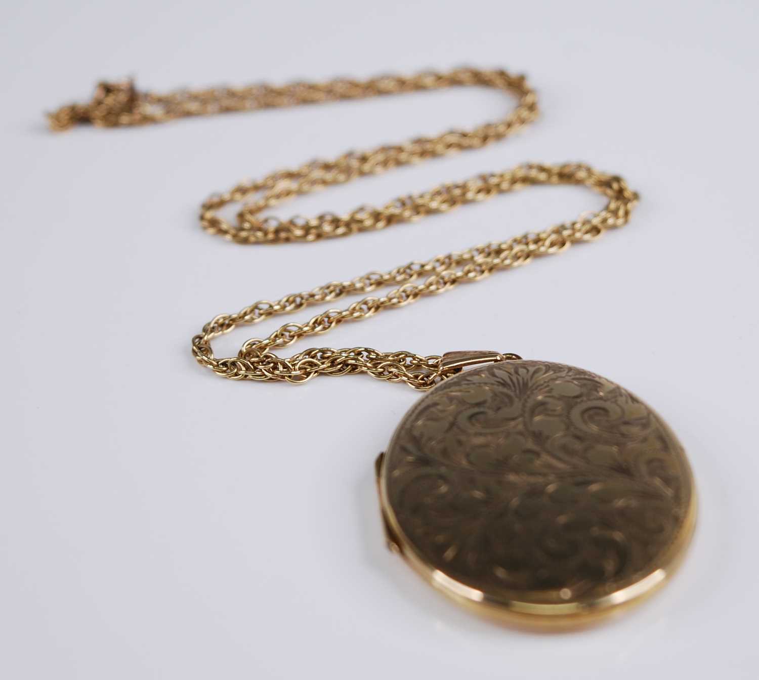 A 9ct yellow gold oval locket, engraved with foliate detail, locket dimensions 42 x 32mm, attached