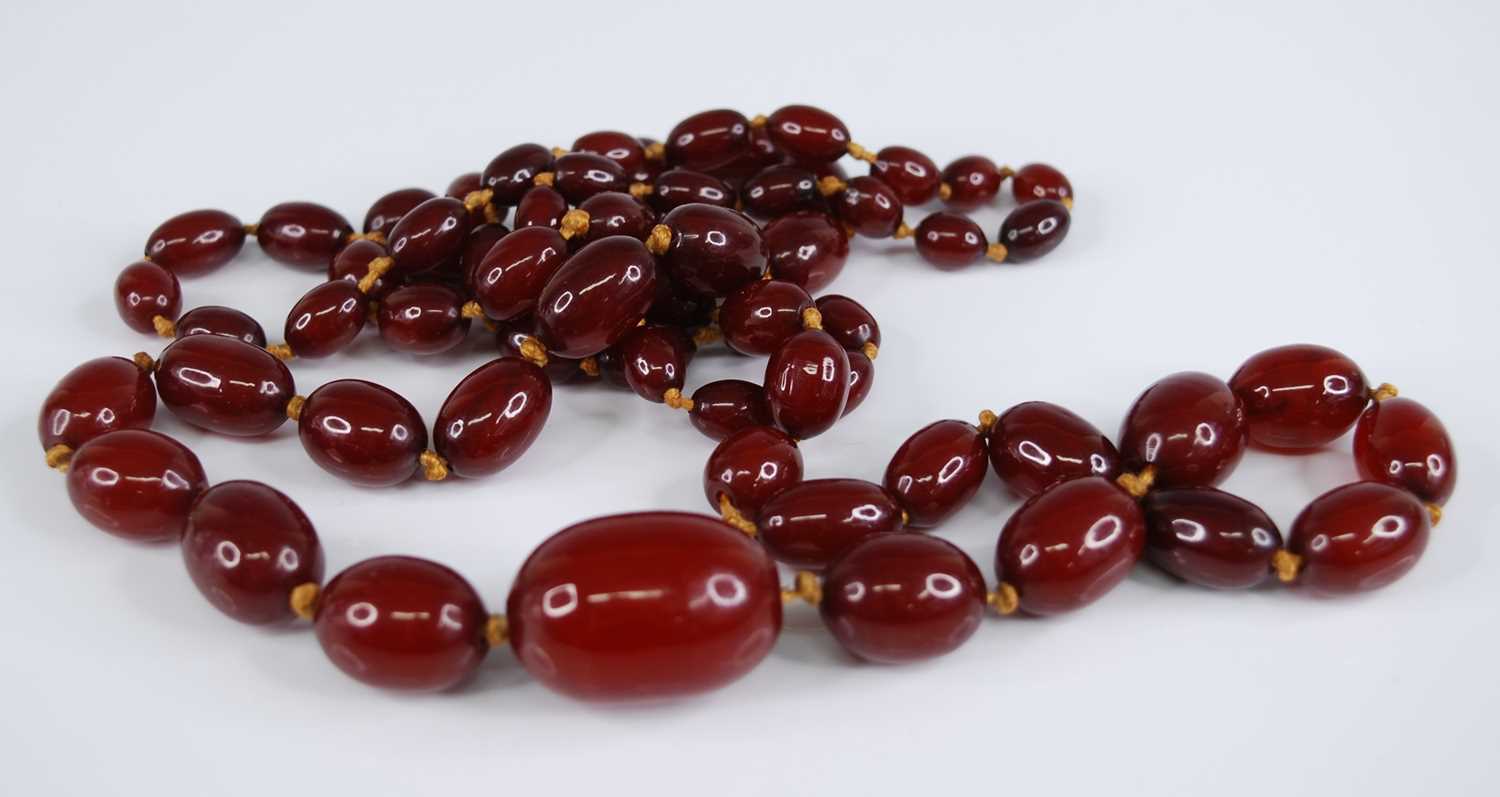 A cherry amber necklace, the 66 graduated barrel beads on a knotted string, gross weight 107g,