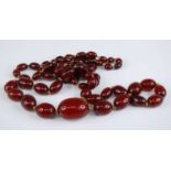 A cherry amber necklace, the 66 graduated barrel beads on a knotted string, gross weight 107g,
