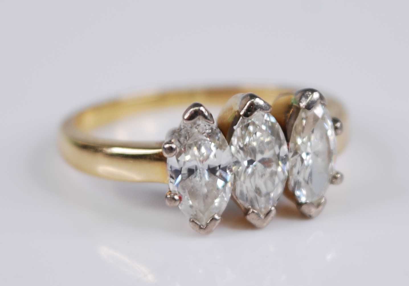 A yellow metal diamond three stone ring, the claw set marquise cut diamonds in a line setting,