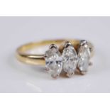 A yellow metal diamond three stone ring, the claw set marquise cut diamonds in a line setting,