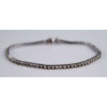 A contemporary 18ct white gold diamond set tennis bracelet, arranged as 76 four-claw set round