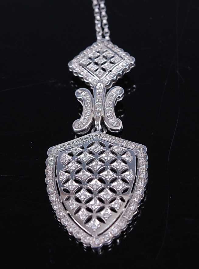 A white metal diamond articulated shield shaped pendant, having 106 melee cut diamonds grain set