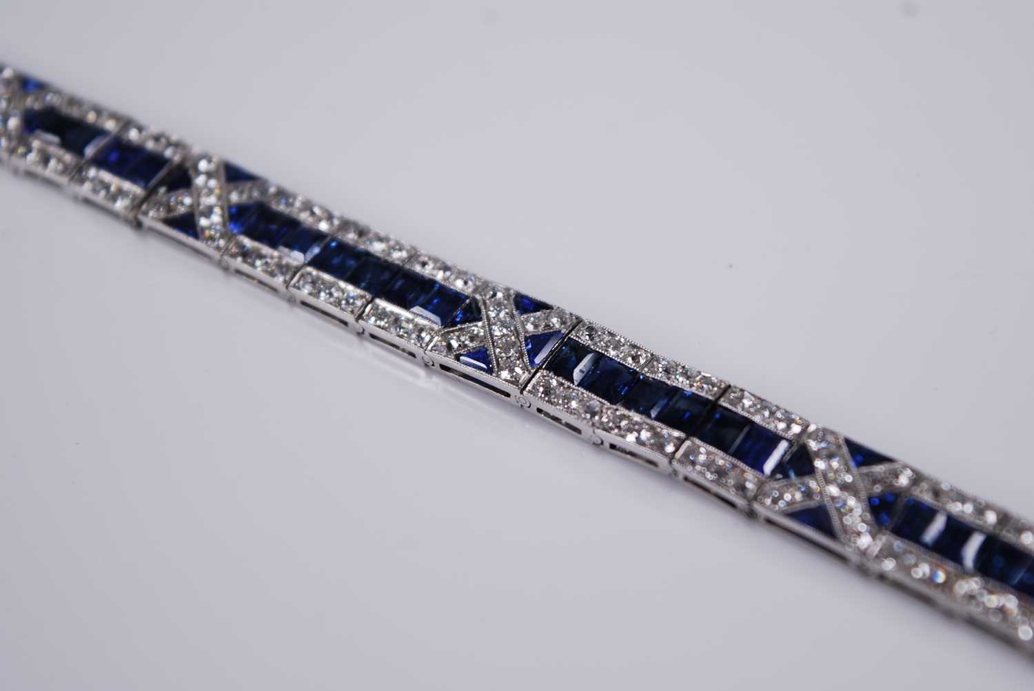 A white metal, sapphire and diamond Art Deco style articulated line bracelet, featuring 57