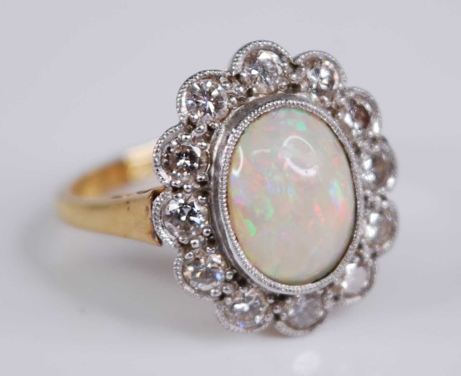 An 18ct gold and platinum, opal and diamond set cluster ring, arranged as a central opal cabochon