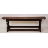 An 18th century and later joined oak long bench, having a single plank top and carved detail frieze,