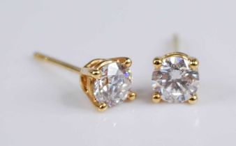 A pair of yellow metal diamond single stone stud earrings, each featuring a round brilliant cut