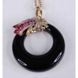 A yellow metal onyx, ruby and diamond pendant, featuring an onyx band surmounted by a cornucopia