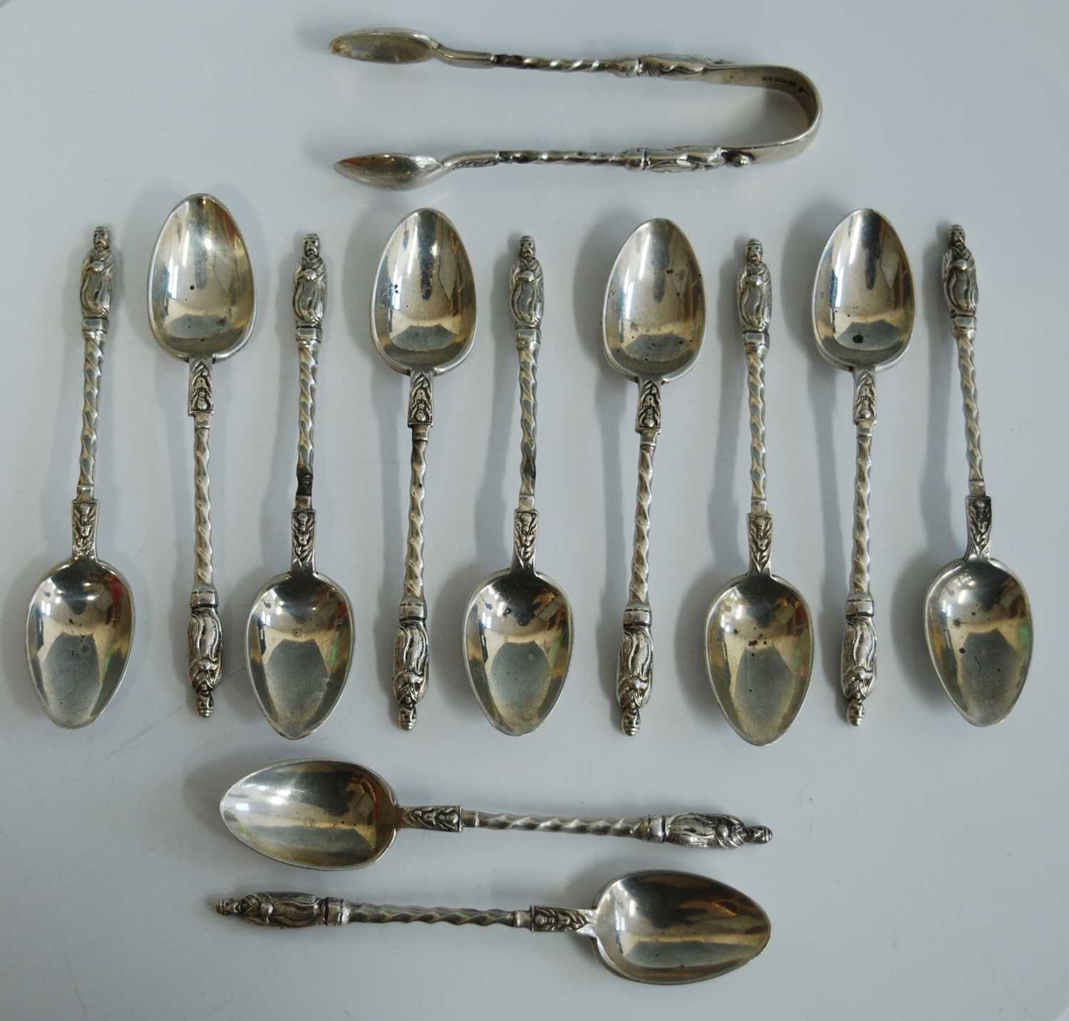 A set of eleven George V silver apostle spoons with matching sugar tongs, having spiral turned stems