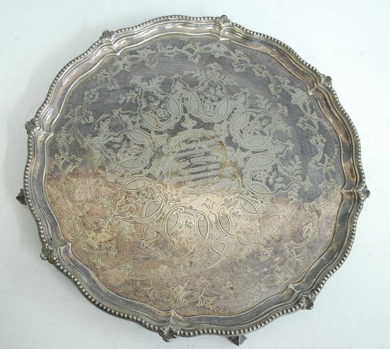 A Victorian silver presentation salver, of shaped circular form standing upon four claw and ball