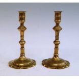 A pair of mid 18th century brass table candlesticks, each having a knopped stem above a petal