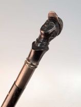 An early 20th century walking stick, the bronze handle in the form of the head of a jockey,