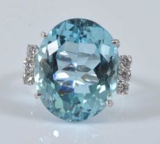 A white metal, aquamarine and diamond ring, comprising a centre oval aquamarine in a four claw