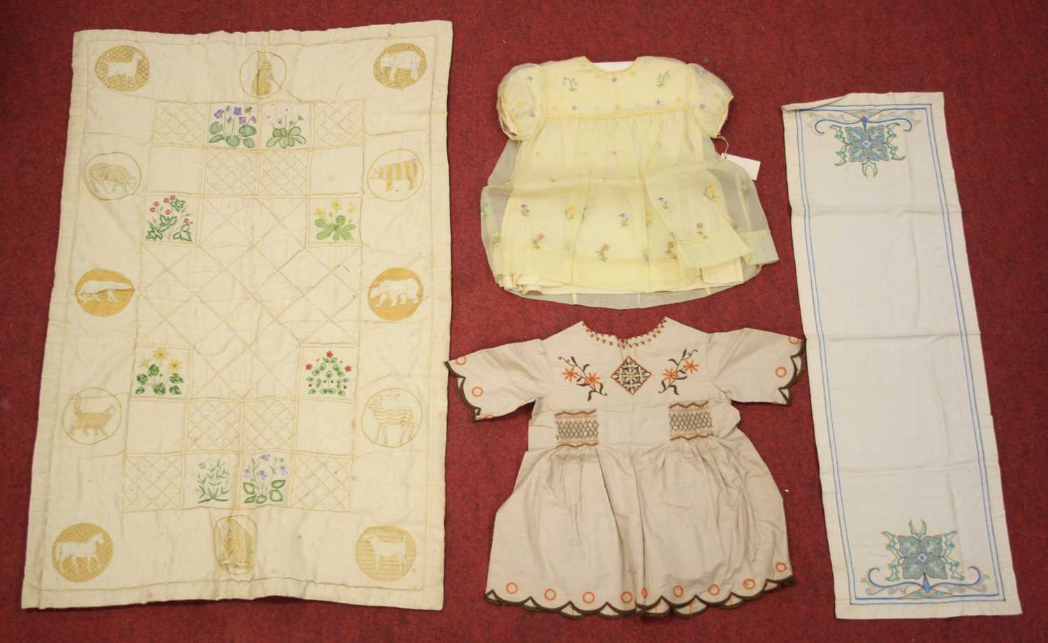 A circa 1900 silk backed and hand-embroidered quilt for a cot, having square panels hand-embroidered