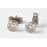 A pair of white metal diamond stud earrings, each comprising a round brilliant cut diamond in a