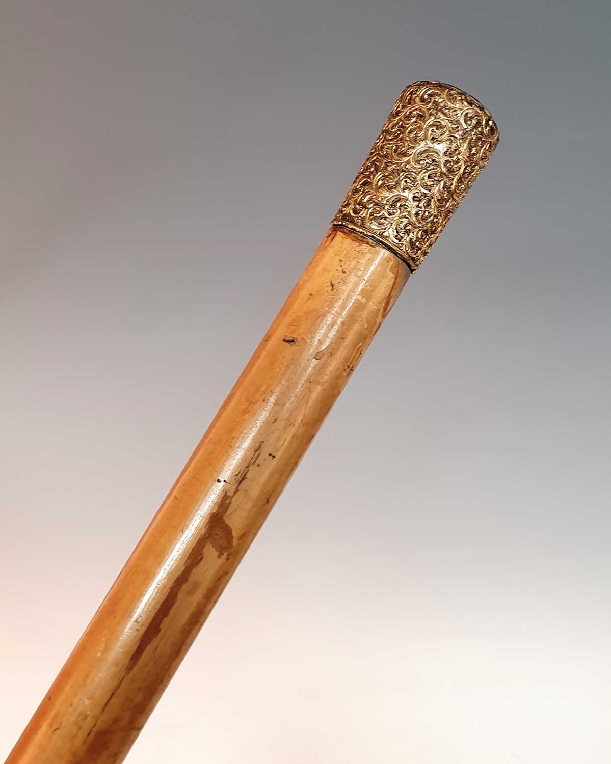 An early 20th century walking/horse measuring stick, the repousse decorated gilt metal handle