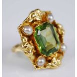 A yellow metal, peridot and pearl dress ring, comprising an emerald cut peridot within an ornate