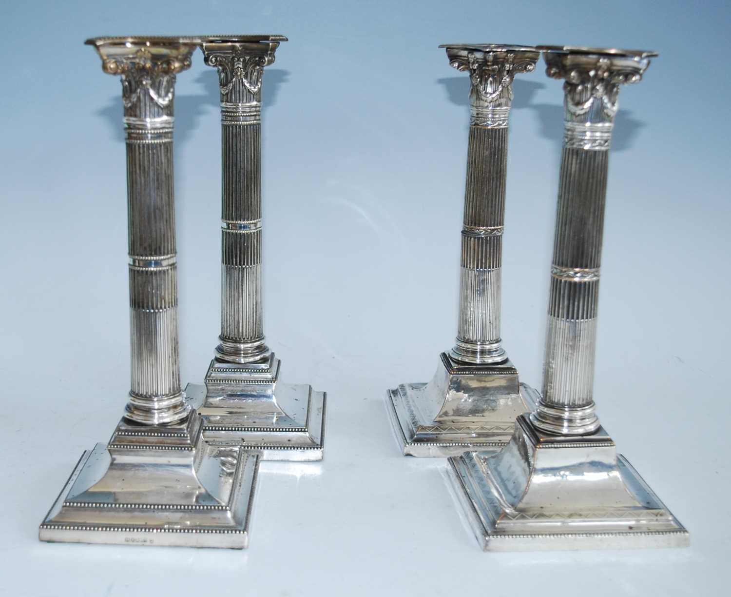 Two pairs of 19th century silver plated candlesticks, each stop fluted column standing upon beaded