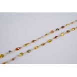 A contemporary yellow metal multicoloured sapphire set long necklace, arranged as 84 bezel set