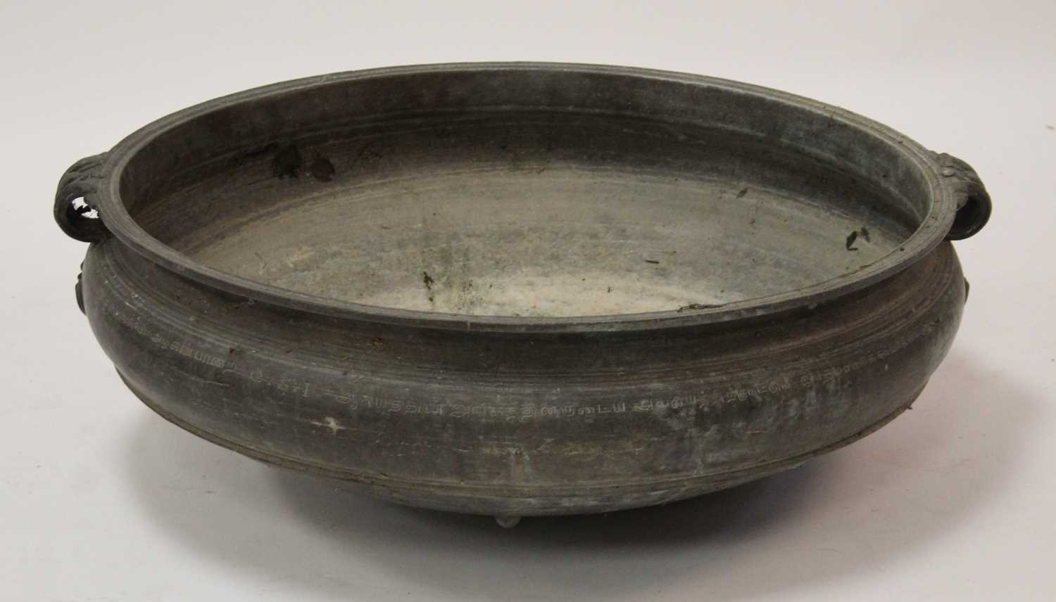 A large Chinese brass twin handled shallow bowl, of slightly shouldered squat form with floral