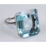A white metal aquamarine single stone ring, having an emerald cut aquamarine in a four-claw setting,