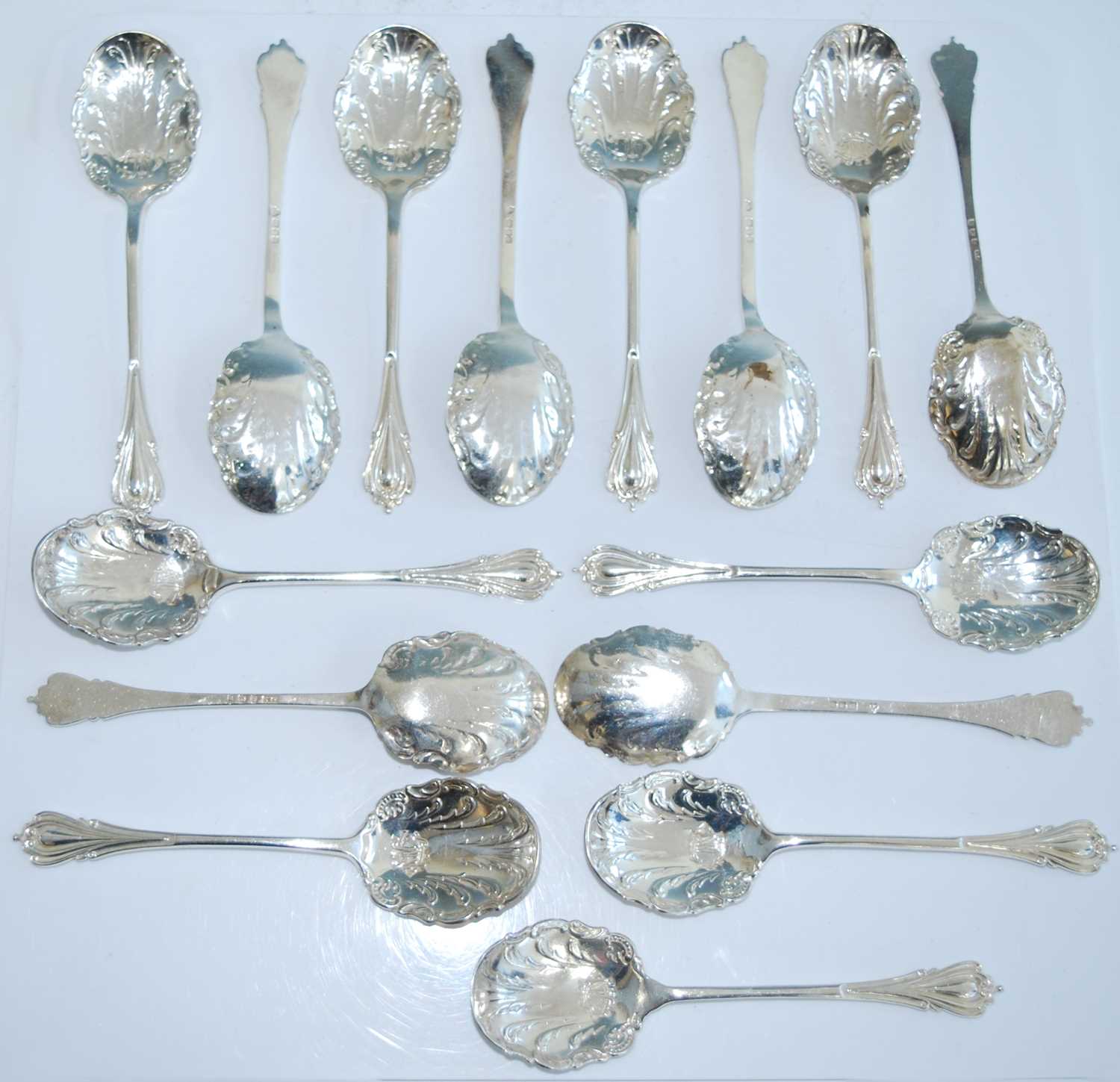 A matched set of fifteen early 20th century silver caddy spoons, the shaped scroll-edged bowls