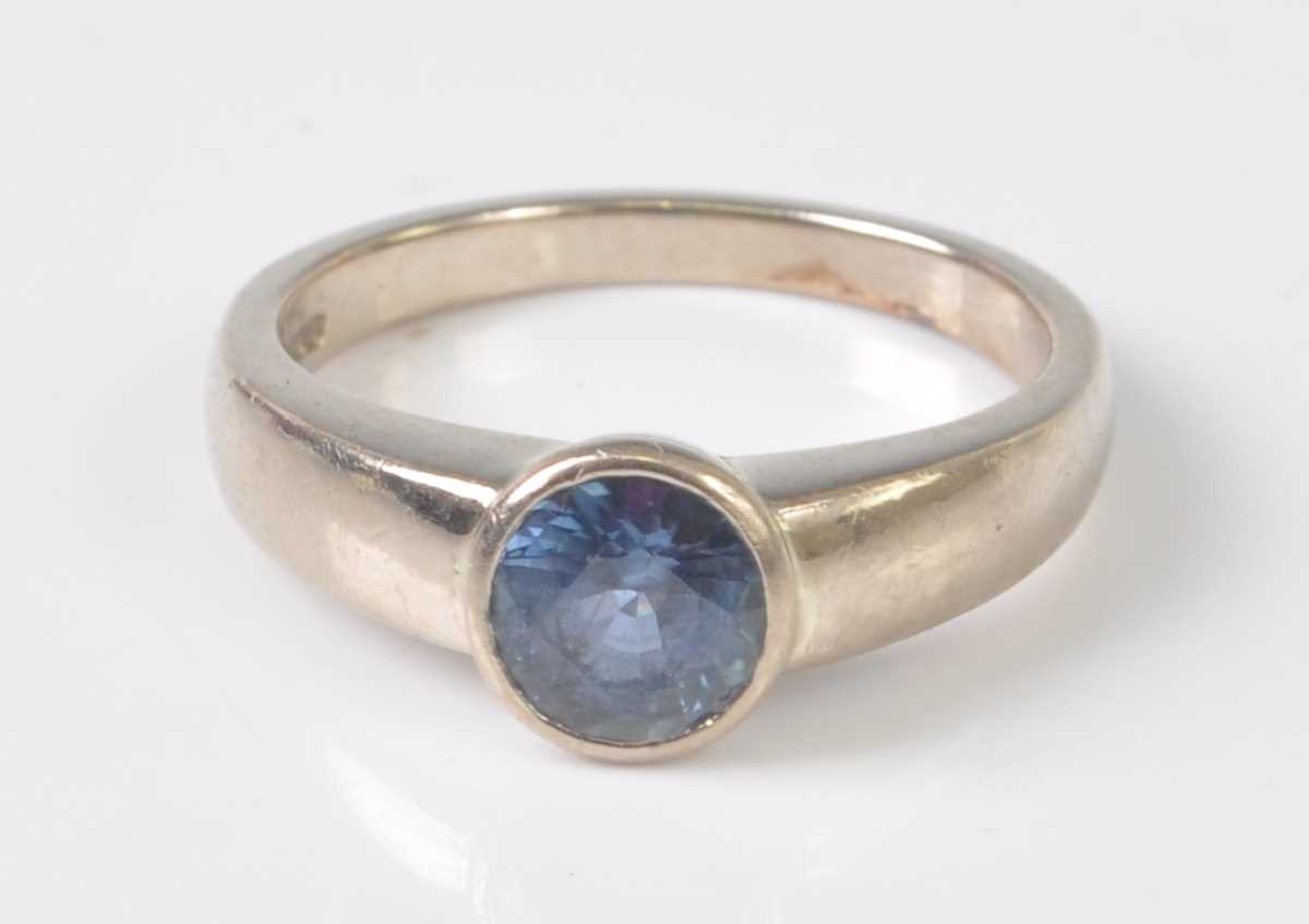 An 18ct white gold sapphire dress ring, the round faceted sapphire in a bezel setting, sapphire