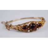 A Victorian style 9ct gold, garnet and seed pearl hinged bangle, the three cabochon garnets