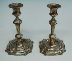 A pair of late Victorian silver table candlesticks, the knopped stems to shaped and stepped square