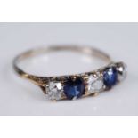A yellow metal, sapphire and diamond half hoop eternity ring, featuring two oval faceted sapphires