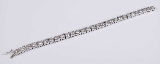 An 18ct white gold diamond set tennis bracelet, arranged as 29 flower head links each illusion set