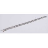 An 18ct white gold diamond set tennis bracelet, arranged as 29 flower head links each illusion set