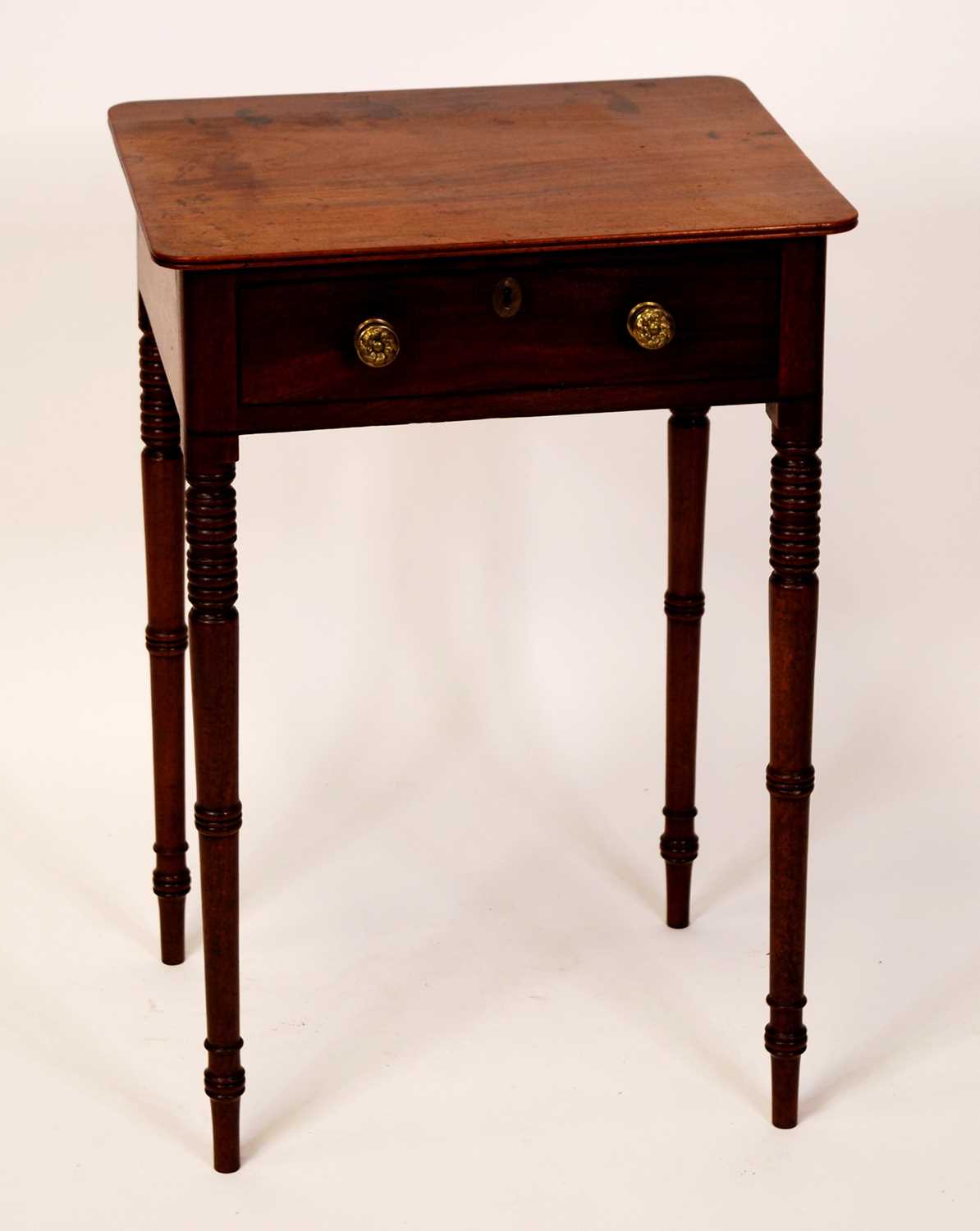 An early 19th century mahogany round cornered single drawer side table, raised on ring turned