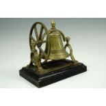 A bell tower style brass dinner bell mounted on a ebonised stand, 18 cm