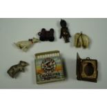 Five charms comprising a carved bone elephant, an early 20th century brass "Fumsup", a gilt metal