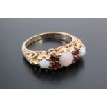 A 1970s opal and garnet ring, comprising three round opal cabochons, the central stone 5 mm, divided