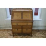 An Arts and Crafts influenced fall front bureau, constructed from light oak and having a gallery