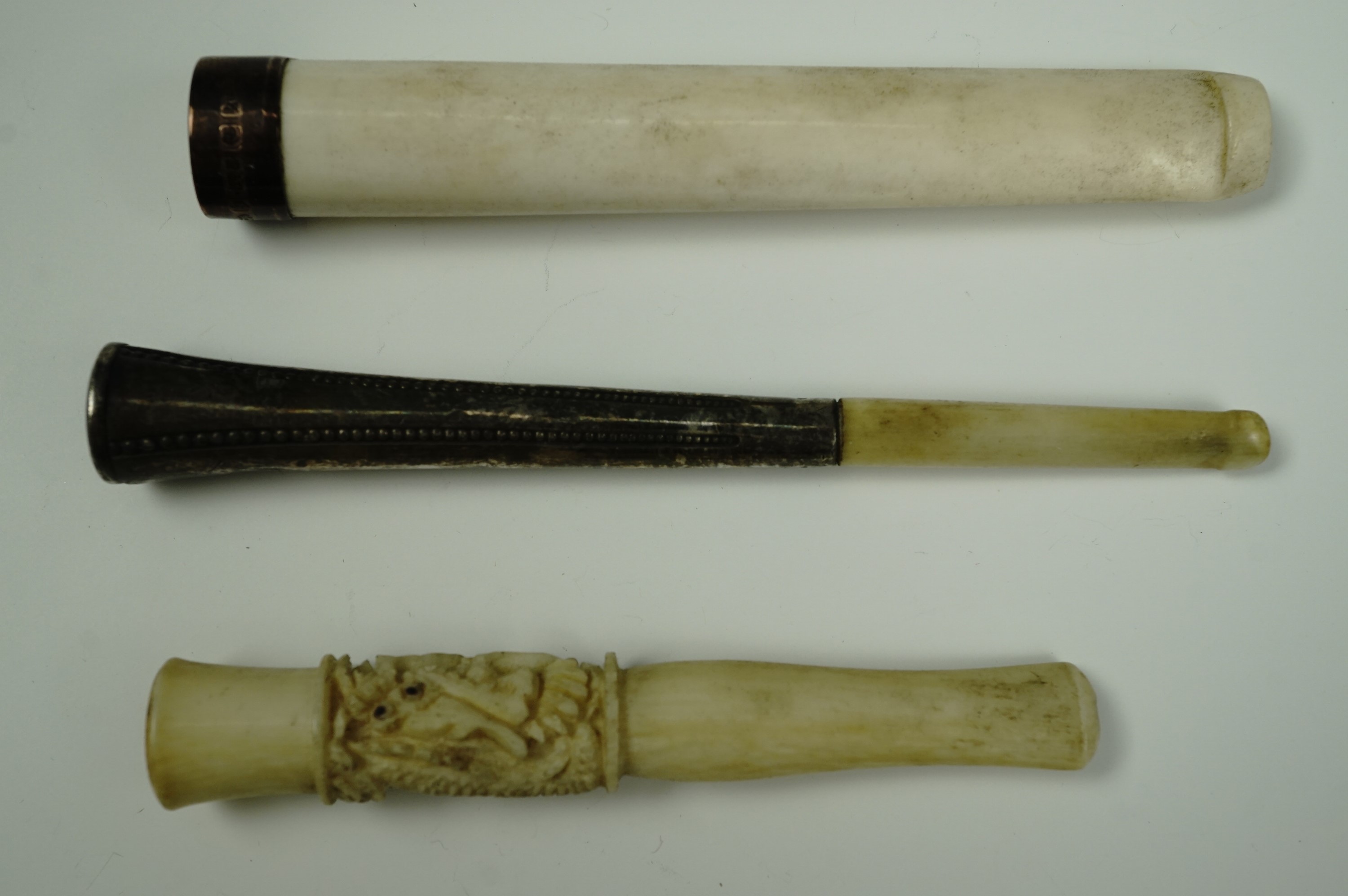 Three Edwardian cheroot holders, variously in ivory and white metal, Indian carved ivory, and 9