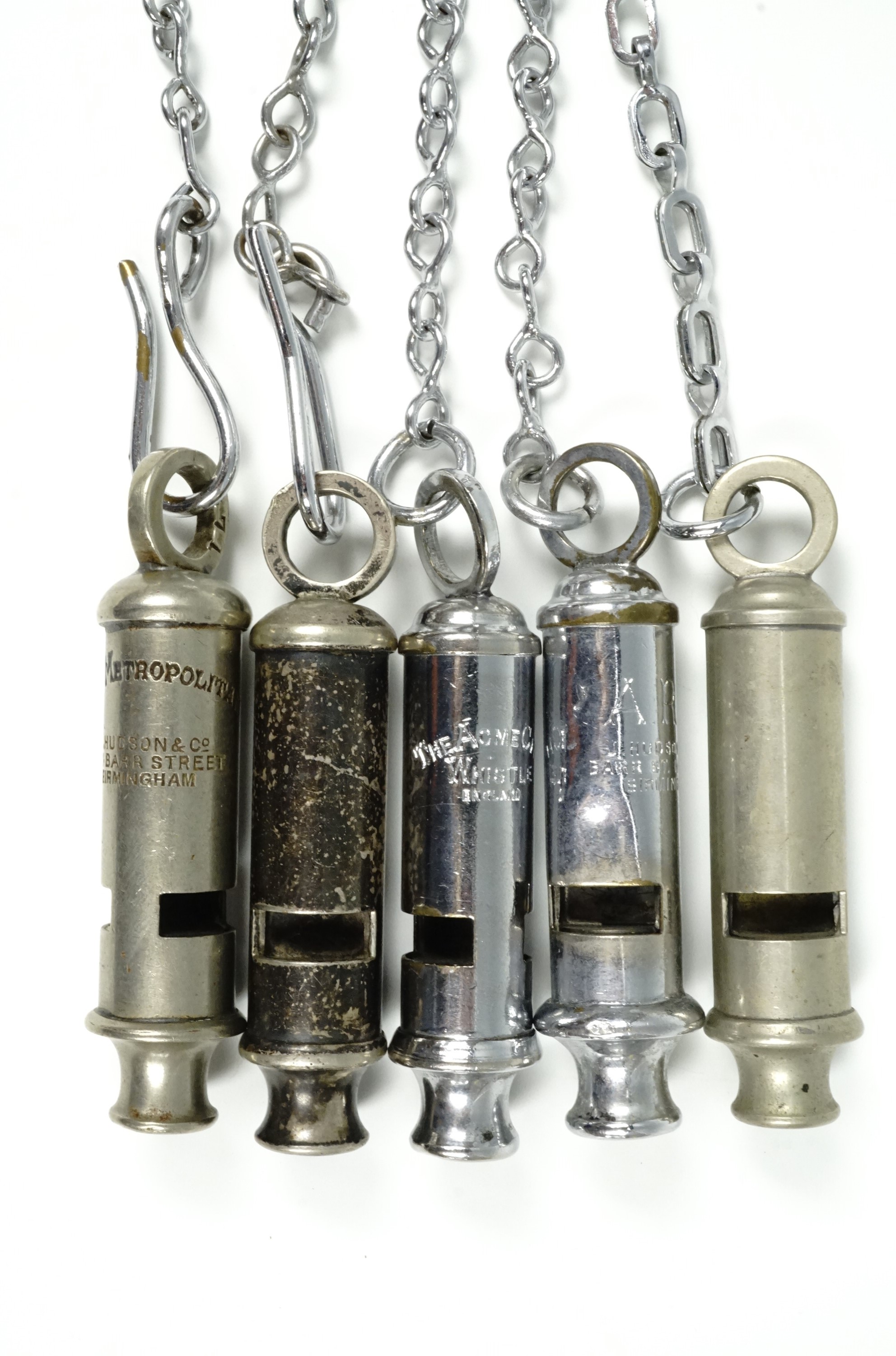 Five police whistles with chains, comprising 'ARP' whistle by Hudson and Co., 'The Metropolitan'